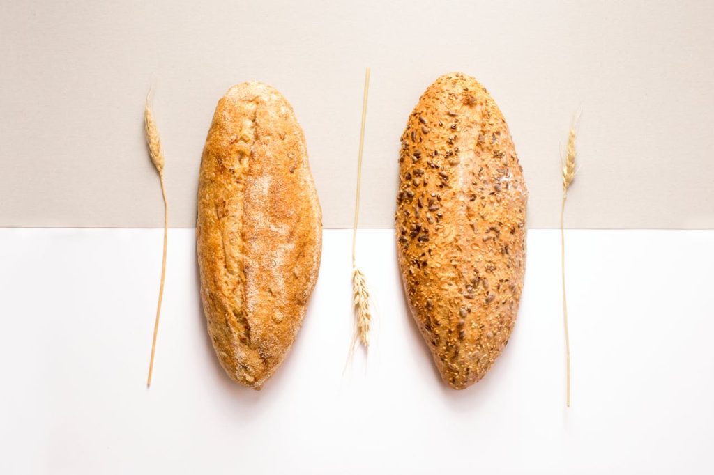 two-baked-breads-1756062 Flat lay image of two artisan bread loaves with wheat decoration on a neutral background.